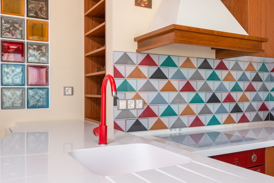 Interior of stylish kitchen with colorful tile and red faucet in modern apartment