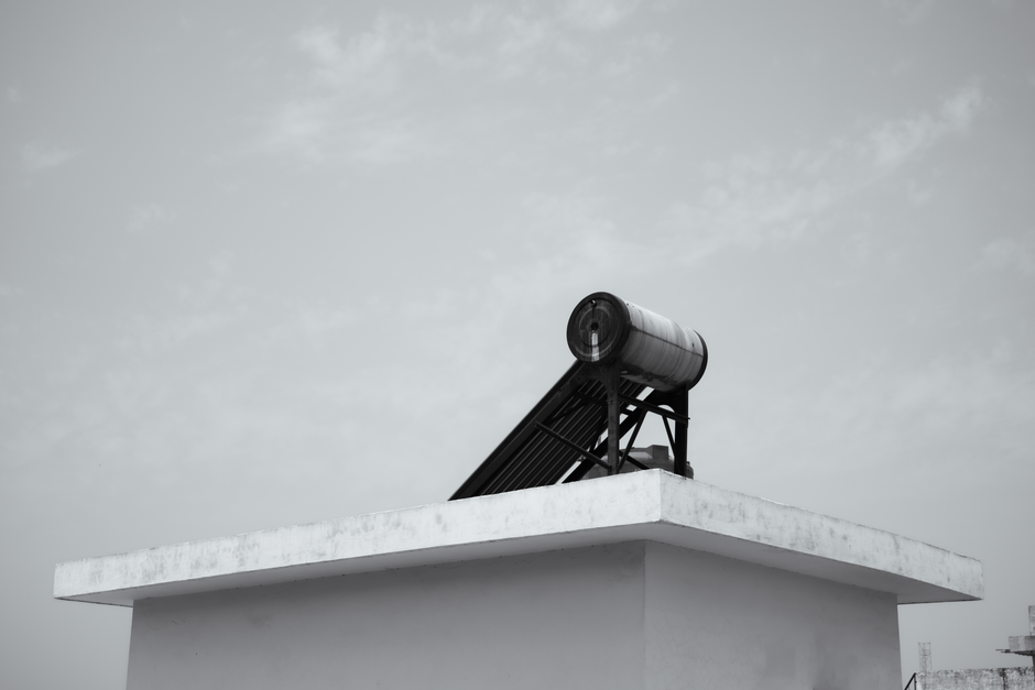 Solar water heater on a rooftop against a clear sky, energy efficient design.